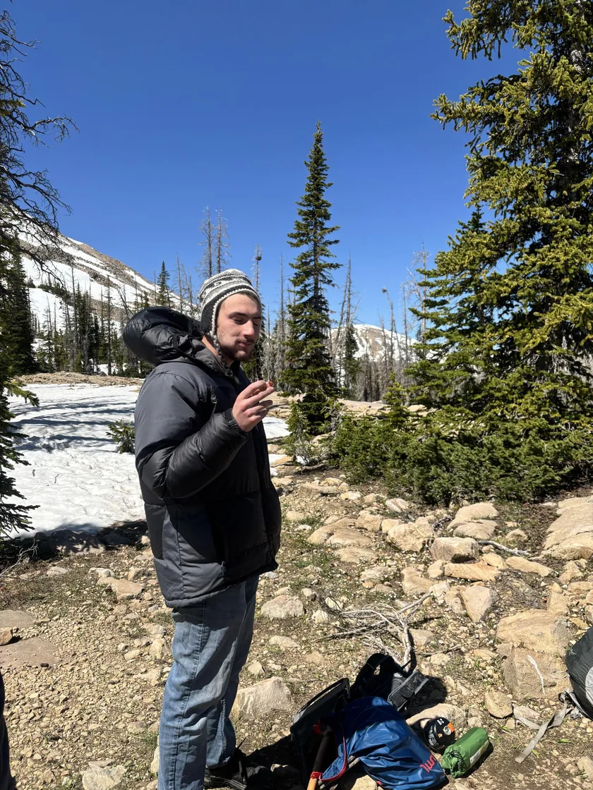 A man in a knit hat and winter jacket on a snowy mountain trail.